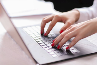 Damenhände tippen auf einer Laptoptastatur